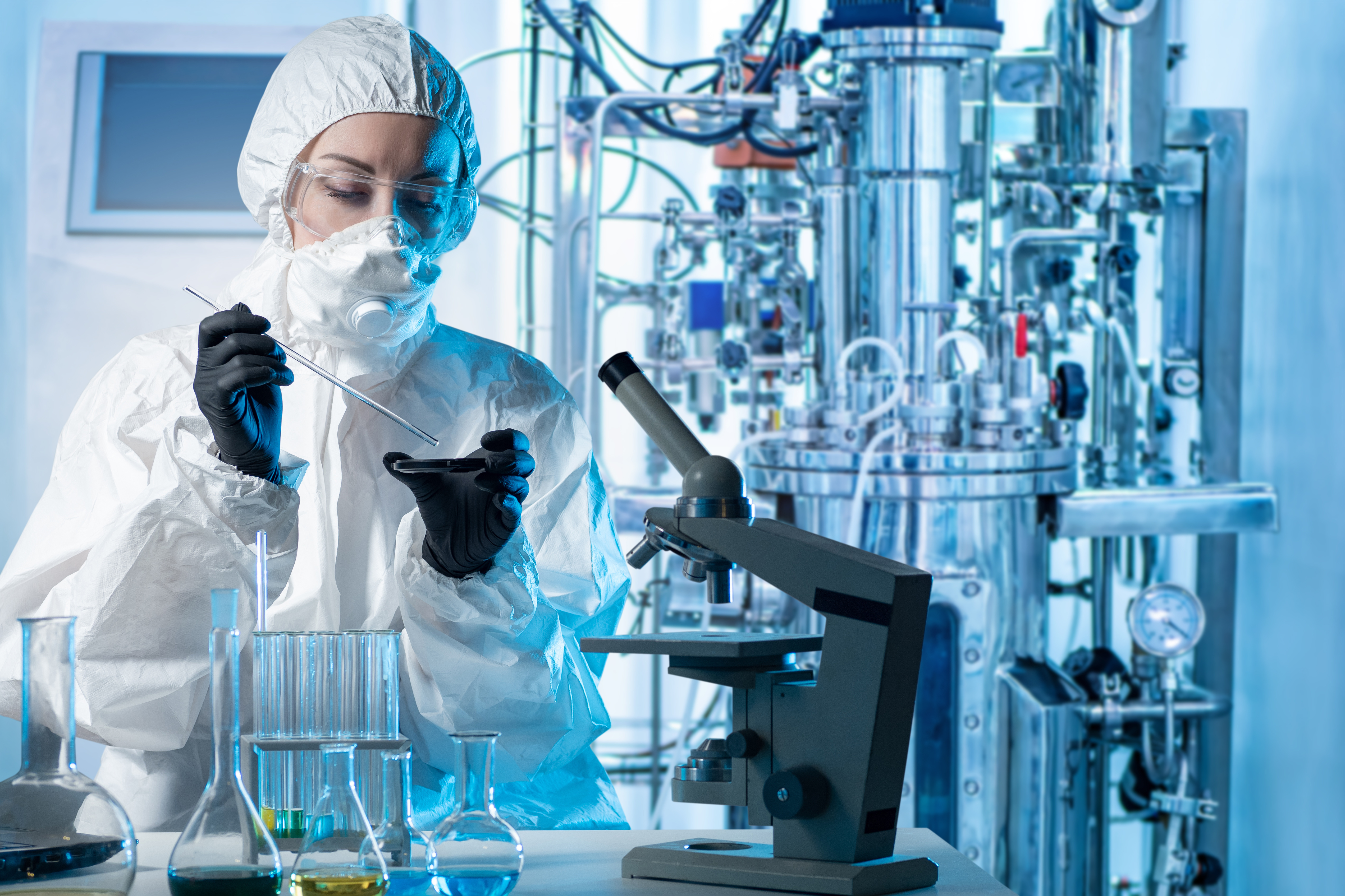 Laboratory assistant with microscope bio tech. Scientist near bioreactor.